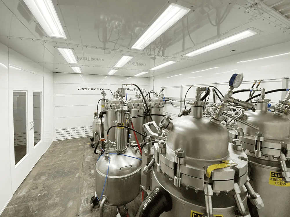 Falling-film evaporator and jacketed collection vessels installed inside a Podtronix-branded distillation room.